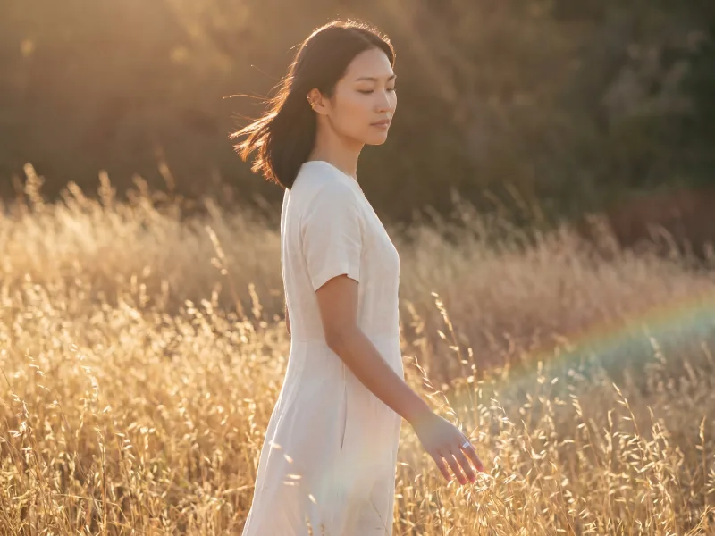 Woman walking through a field of tall grass at golden hour